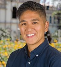 A headshot photo of Josen smiling, wearing a blue button-up shirt