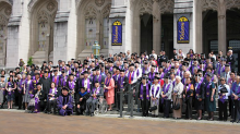 Former UW students from the Long Journey Home Ceremony stand on the steps of Suzzallo and Allen Libraries in graduation attire
