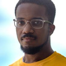 Victor Luckerson facing the camera wearing clear glasses and a yellow shirt