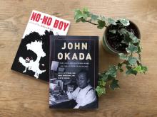 View from above of two books, NO-NO BOY and JOHN OKADA, next to a potted plant on a wooden tabletop