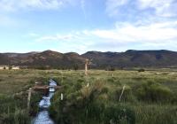 Acequia de los Vallejos in southern Colorado’s San Luis Valley with hills in the background and blue skies with some clouds