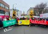 A group of individuals stand behind several horizontal signs in a march in Seattle's Chinatown International District