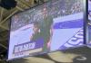 Photo taken of the jumbotron showing JP with his son on the basketball court smiling and the crowd looking on