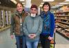 Dr. Peña and two other individuals stand in front of market products smiling